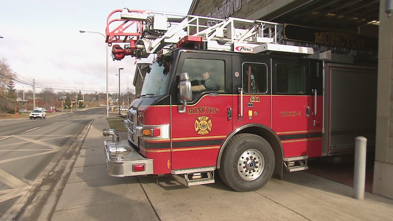 A red fire truck being backed into a garage bay of a fire station. It's three-quarters of the way in.