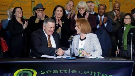 Seattle Mayor Jenny Durkan, right, shakes hands with Oak View Group CEO Tim Leiweke after they signed an agreement to renovate KeyArena. On Thursday, the NHL agreed to accept an expansion application from the city. seattle-nhl-expansion-120717