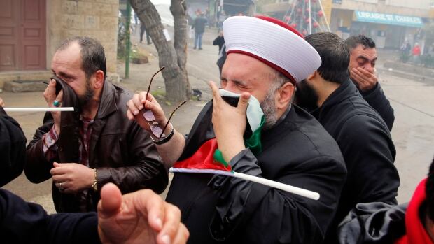Protesters take cover from tear gas fired by riot police during a demonstration in front of the U.S. embassy in east of Beirut