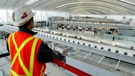 Aecon Construction scissor lift operator, Abel Sousa, looks at Toronto Pearson International Airport's new Terminal 1 check-in area from above the scissor lift on Tuesday Dec. 2, 2003. The Trudeau Liberals are facing warnings to proceed cautiously and in as transparent a manner as possible as it weighs a Chinese state owned company's bid to take over Aecon construction. The warnings come in the face of strong affirmations by the Liberal government that Canada's pursuit of deeper trade relations with China is full steam ahead despite suggestions that could risk angering the Trump administration during the North American Free Trade renegotiations. Cda China 20171029