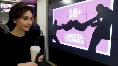 A woman walks past a monitor displaying the Death of Stalin movie trailer before a screening of the film on Jan. 24. The film had been banned from being shown in cinemas of the country.<br />
<br />
RUSSIA-FILM/STALIN