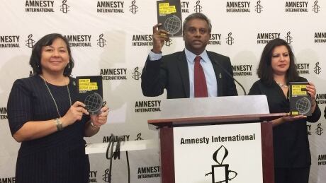 Amnesty's secreatry general Salil Shetty, second from left, holds a copy of the annual report that the organization released in Washington on Wednesday. Shelty said there haven't been sufficient penalties and censures internationally to discourage hate. Amnesty International Americas