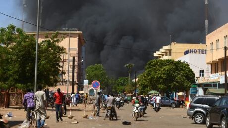 People watch smoke rising as the capital of Burkina Faso came under multiple attacks on March 2, 2018, targeting the French embassy, the French cultural centre and the country's military headquarters. AFP_11N620