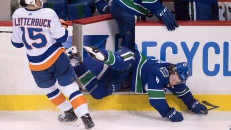 The Islanders' Cal Clutterbuck checks Canucks rookie forward Brock Boeser during the third period of Monday's game. Boeser hurt his lower back on the open gate of Vancouver's bench and will need four to six weeks to recover, the team said. HKN Islanders Canucks 20180305