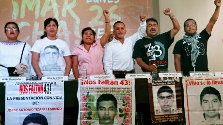 Relatives of 43 missing students from the Isidro Burgos Rural Normal School of Ayotzinapa hold up their fists behind photos of their missing family members at a press conference in Mexico City, Thursday, Sept. 15, 2016. The former head of investigations for the Mexican Attorney General's Office, Tomas Zeron, who has been criticized for his handling of the case of the disappeared students, was named a national security adviser hours after he resigned his previous post. The students were in Iguala on Sept. 26, 2014 to hijack buses to use for transportation to a rally in Mexico City when they were attacked on the buses by local police and allegedly handed over to members of the Guerreros Unidos cartel. (AP Photo/Marco Ugarte) Mexico Missing Students