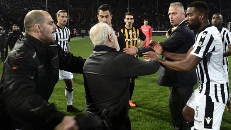 PAOK's Greek-Russian president Ivan Savvidis, middle, takes to the pitch carrying a handgun in his waistband after the referee refused a last minute goal on March 11, during a Greek Superleague match against AEK Athens. Greece faces expulsion from international competitions because of widespread violence. savvidis-ivan-180311-1180