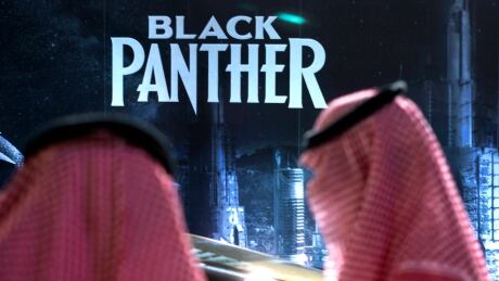 Visitors wait in front of a "Black Panther" movie banner, during an invitation-only screening, at the King Abdullah Financial District Theater, in Riyadh, Saudi Arabia, Wednesday, April 18, 2018. Saudi Arabia held a private screening of the Hollywood blockbuster "Black Panther" Wednesday, to herald the launch of movie theaters that are set to open to the public next month. (AP Photo/Amr Nabil) Saudi Cinema