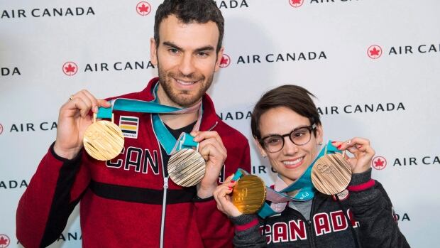 Figure skaters Meagan Duhamel, right, and Eric Radford, left, are seen showing their medals from the Pyeongchang Games after arriving in Montreal in February. The duo officially retired on Wednesday. duhamel-radford-022618-620