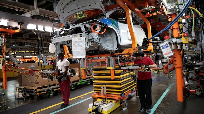 General Motors assembly workers connect a battery pack underneath a partially assembled 2018 Chevrolet Bolt EV vehicle on the assembly line at Orion Assembly in Lake Orion, Mich.