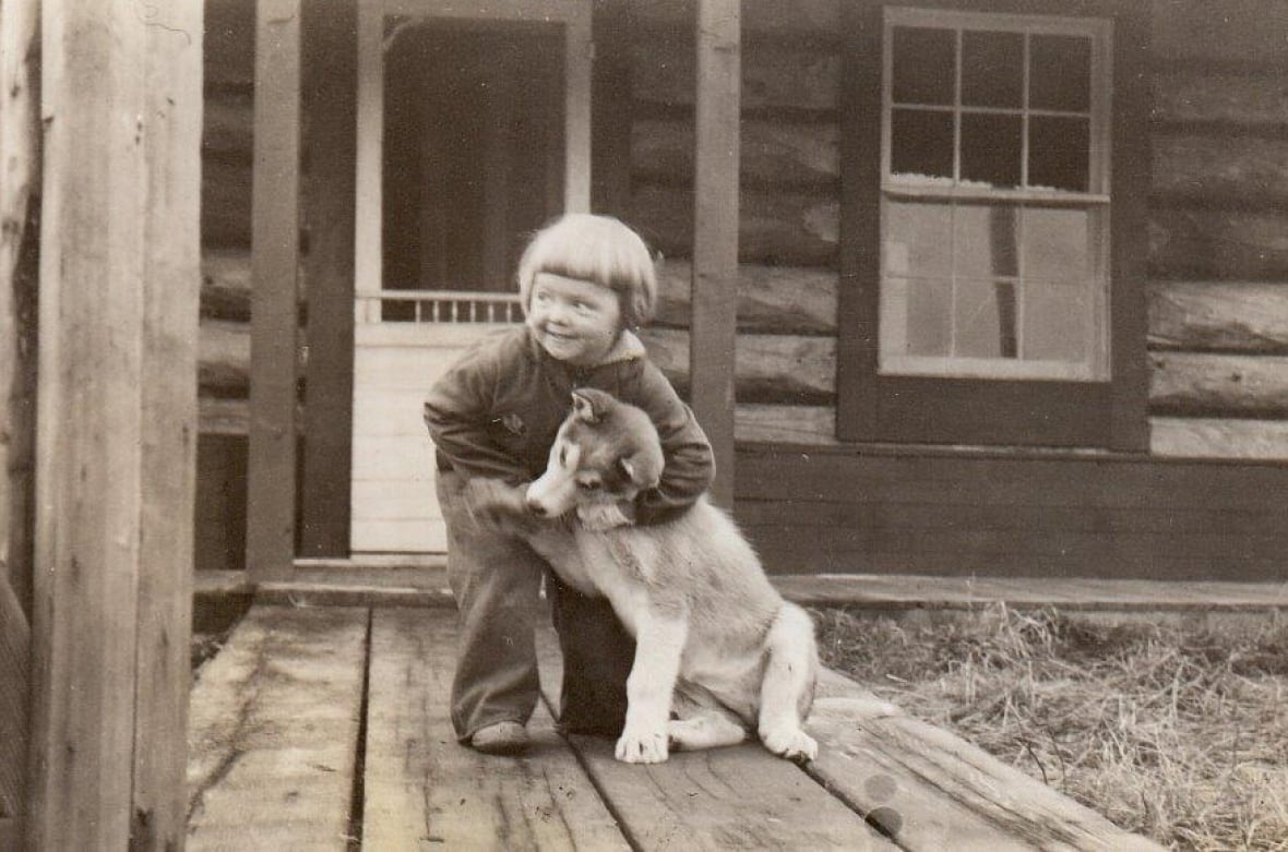 A black and white photo of a young girl and a dog.