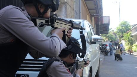 Police aim their weapons at a man who was being searched by other police officers following an explosion at nearby police headquarters in Surabaya, Indonesia May 14, 2018 in this photo taken by Antara Foto. Antara Foto/ Didik Suhartono / via REUTERS ATTENTION EDITORS - THIS IMAGE WAS PROVIDED BY A THIRD PARTY. MANDATORY CREDIT. INDONESIA OUT. TPX IMAGES OF THE DAY - RC16C418C620 INDONESIA-BOMB/POLICE