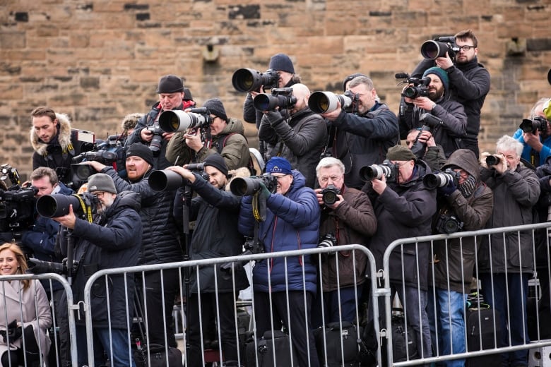 Many photographers take pictures from behind a gate. 