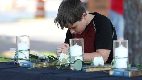 A young boy prays during a vigil held at the Texas First Bank after a shooting left several people dead at Santa Fe High School in Santa Fe, Texas, U.S., May 18, 2018. TEXAS-SHOOTING/