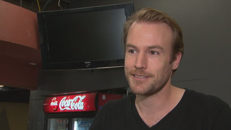 A man standing in front of a Coca Cola cooler.