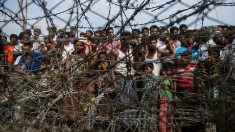 TOPSHOT - This picture taken from Maungdaw district, Myanmar's Rakhine state on April 25, 2018 shows Rohingya refugees gathering behind a barbed-wire fence in a temporary settlement setup in a "no man's land" border zone between Myanmar and Bangladesh. - A United Nations Security Council delegation which wants to see first-hand the impact of the Rohingya refugee crisis will arrive in Myanmar on April 30 and visit Rakhine state, a senior government official said. Myanmar and Bangladesh signed a repatriation deal for refugees to return in January but so far only one family has returned from a no man's land between the two nations. (Photo by Ye Aung THU / AFP) (Photo credit should read YE AUNG THU/AFP/Getty Images) AFP_14B9W0