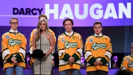 Christina Haugan and surviving members of the Humboldt Broncos accept the Willie O'Ree Community Hero Award for her late husband Darcy, coach of the team who was killed in a bus crash on April 6 that also left 15 others dead.
775179098MW00132_2018_NHL_A