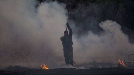 An Israel soldier extinguishes a fire started by a kite with attached burning cloth launched by Palestinians from Gaza, a near the Israel and Gaza border, Friday, June 1, 2018. Israel Palestinians