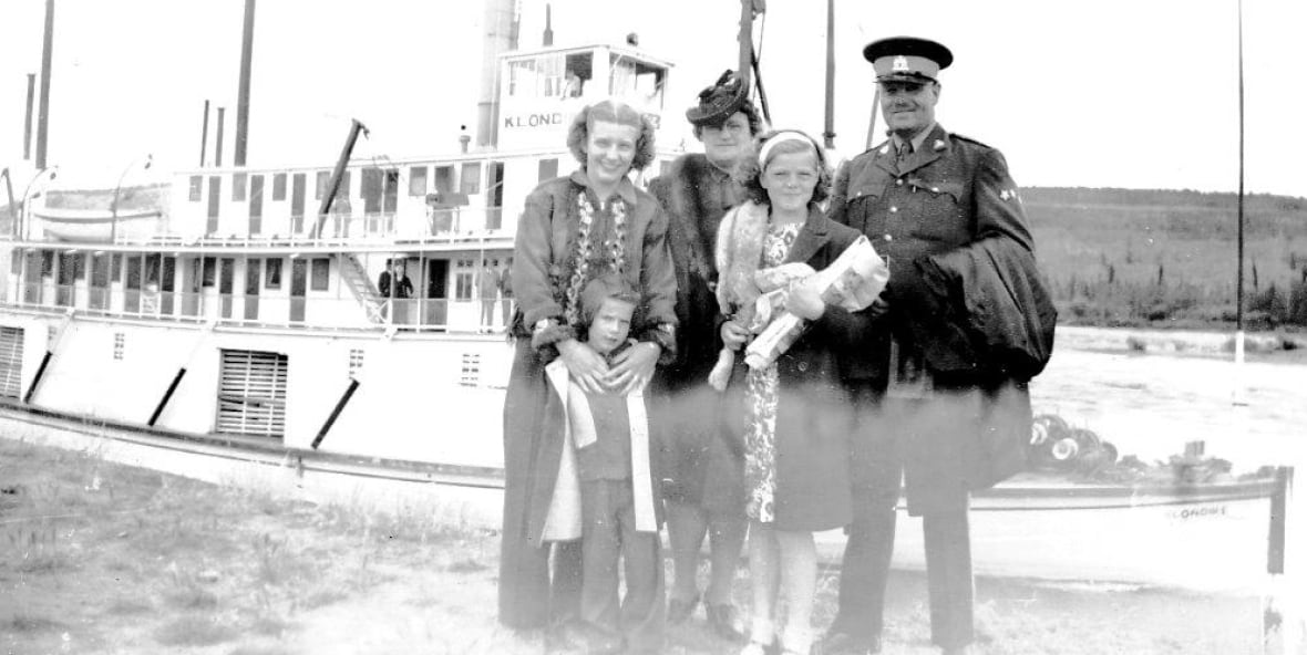 A black and white photo of a family sanding by a ship.