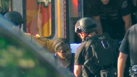 In this image from video provided by KNBC-TV, a suspect waits to be placed in an ambulance outside a Trader Joe's supermarket in the Silver Lake district of Los Angeles on Saturday, July 21, 2018. Supermarket Standoff