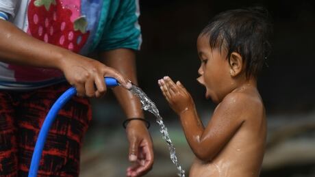 A woman bathes a child at a shelter for earthquake victims in Santong Village, Kayangan, Lombok, Indonesia on Aug. 11.<br />
INDONESIA-QUAKE/