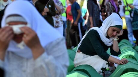 Bosnian women offers prayers near the caskets of 71 victims of the 1995 Srebrenica massacre, at the memorial cemetery in the village of Potocari, near the town of Srebrenica, on July 11, 2017. AFP_QH80I