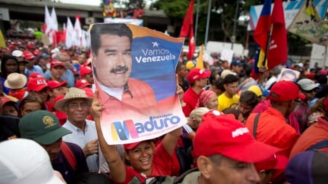 A supporter of Venezuela's President Nicolas Maduro holds up his picture during a rally in Caracas, Venezuela, Monday, Aug. 13, 2018. The United Socialist Party of Venezuela (PSUV) organized the rally to show support for the president following what the government called a failed assassination attempt with explosives-laden drones. Venezuela Maduro