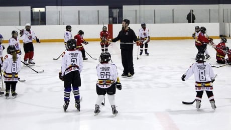 Hockey Education Reaching Out Society (HEROS) program manager Kevin Hodgson, centre, works with disadvantaged kids during an on-ice session in Calgary, Alta., Thursday, Dec. 20, 2012. THE CANADIAN PRESS/Jeff McIntosh hockey-coach-1180