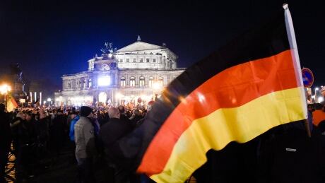 A demonstrator holds a German national flag as he attends with other protestor a demonstration of the PEGIDA (Patriotic Europeans against the Islamization of the West), in front the Semperoper opera house in Dresden, Monday, Oct. 26, 2015. (AP Photo/Jens Meyer) Germany Anti-Islam Protests