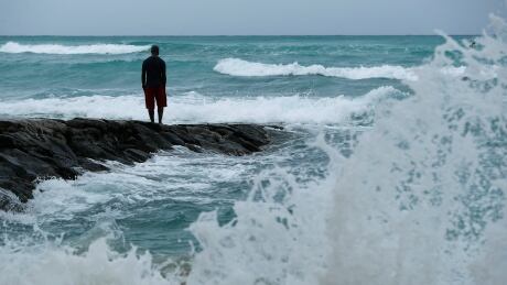 A man stands along the beach as waves crash on shore before Hurricane Lane, Thursday, Aug. 23, 2018, in Honolulu, Hawaii. A powerful hurricane unleashed torrents of rain and landslides Thursday that blocked roads on the rural Big Island but didn't scare tourists away from surfing and swimming at popular Honolulu beaches still preparing get pummeled by the erratic storm. (AP Photo/John Locher) Hurricane Lane Hawaii