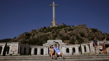 A couple take a photo at the Valley of the Fallen monument at El Escorial, in El Escorial, Spain, on Aug. 24, 2018. Spain's government has approved legal amendments that it says will ensure the remains of former dictator Gen. Francisco Franco can soon be dug up and removed from a controversial mausoleum. Spain Franco's Remains