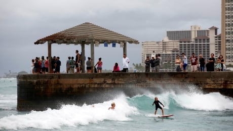 Tourists watch surfers in Waikiki Bay as Tropical Storm Lane approaches Honolulu, Hawaii, U.S. August 24, 2018. REUTERS/Terray Sylvester TPX IMAGES OF THE DAY - RC1F2F4BB860 Hurricane Lane Hawaii WAikiki