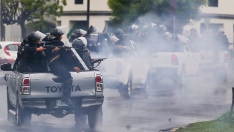 In this May 28, 2018 file photo, police in riot gear riding on the back of pickup trucks fire their shotguns towards university students in Managua protesting Nicaragua's President Daniel Ortega. More than 300 people have been killed in violence since mid-April. Nicaragua Unrest