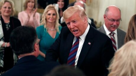 President Donald Trump, cenre, greets people as he arrives to speak during a dinner for evangelical leaders in the State Dining Room of the White House on Monday. Trump