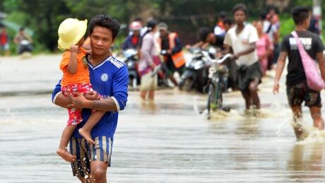 Residents negotiate a flooded road after rampaging waters from Swar Chaung dam submerged villages in Bago region, central Myanmar on August 29, 2018. AFP_18O5JV
