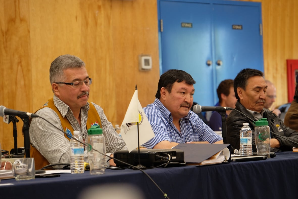Three men sit at a table.
