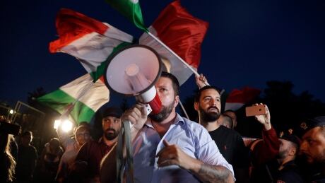 Far-right wing Casapound's activists wave Italian flags in Rocca di Papa, near Rome, Tuesday, Aug. 28, 2018. Approximately 100 refugees and migrants who disembarked from the Italian coast guard ship 'Diciotti' on Sunday after a 10 day standoff are expected to arrive in Rocca di Papa reception center on Tuesday evening. (AP Photo/Gregorio Borgia) Italy Europe Migrants