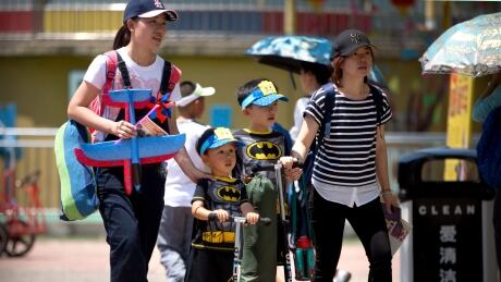 Women walk with children wearing matching outfits at a public park on International Children's Day in Beijing, on June 1, 2018. China announced Monday, Sept. 10, 2018, that it is eliminating a trio of agencies responsible for enforcing family planning policies in a further sign the government may be planning to scrap long-standing limits on the number of children its citizens can have. China Family Planning