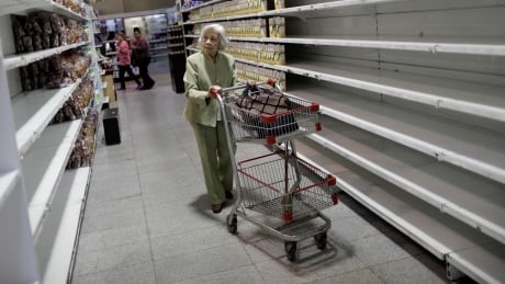An elderly woman walks down a sparsely stocked aisle in a Caracas supermarket on July 25, 2017. VENEZUELA-POLITICS/