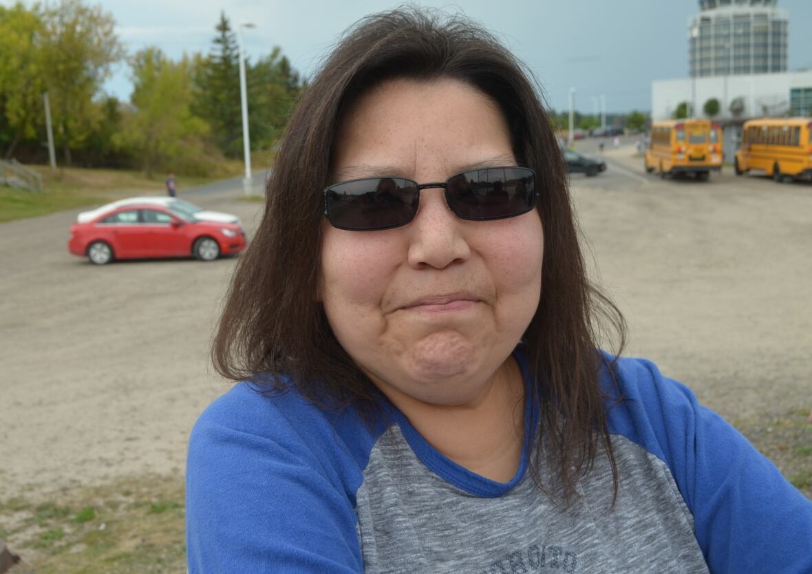a woman in a grey and blue shirt takes a selfie