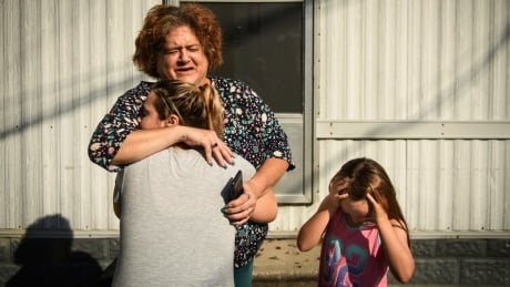 Melanie Wensel gives her neighbor Linda Remmel a hug as Wensel's daughter Emily stands near, Thursday, Sept. 20, 2018, at Speranza Mobile Home Park off of Manchester Road in Spring Lake, N.C. Most of the residents of the park had their homes flooded from Florence and will have to find a new place to live. APTOPIX Tropical Weather North Carolina