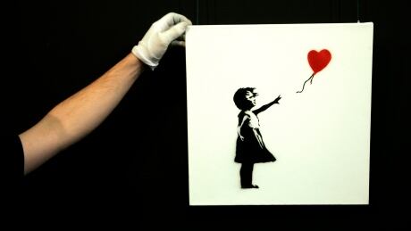 A gallery technician adjusts Banksy's artwork "Balloon Girl" (1975) at Sotheby's auction house at Olympia in London February 2, 2007. The piece is expected to fetch between $14,000 - $20,000 when it is auctioned on February 7. REUTERS / Luke MacGregor (BRITAIN) - GM1DUNGUWRAA BRITAIN/