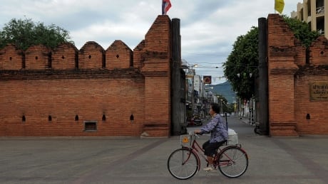 A Thai woman rides her bicycle past the Tha Phae gate in Chiang Mai, some 700kms from Bangkok on May 23, 2010. Thailand's Prime Minister Abhisit Vejjajiva said that the country was calm and returning to normal, and that schools, streets and government agencies would reopen. AFP PHOTO/ MANAN VATSYAYANA (Photo credit should read MANAN VATSYAYANA/AFP/Getty Images) Hkg3607149
