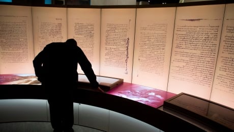 Visitors look at an exhibit about the Dead Sea scrolls during a media preview of the new Museum of the Bible, a museum dedicated to the history, narrative and impact of the Bible, in Washington, DC, November 14, 2017. AFP_UA05E