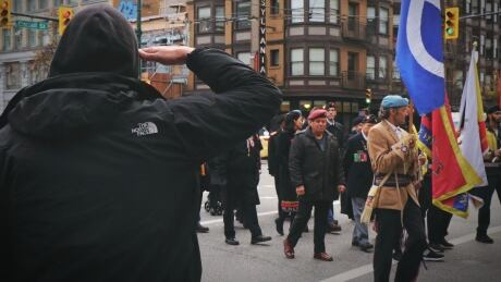 A man stands and salutes the veterans passing by on Hastings Street in Vancouver. Man stands and gives a salute