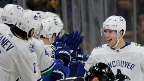 Vancouver Canucks players on the bench reach out to defenceman Ben Hutton (27) to celebrate his goal during the second period of Thursday night's game in Boston. canucks-bruins
