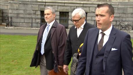 Clerk of the House Craig James, centre, is escorted out of the legislature after he and B.C.'s Sergeant-at-Arms Gary Lenz were placed on leave.  Clerk of the House Craig James