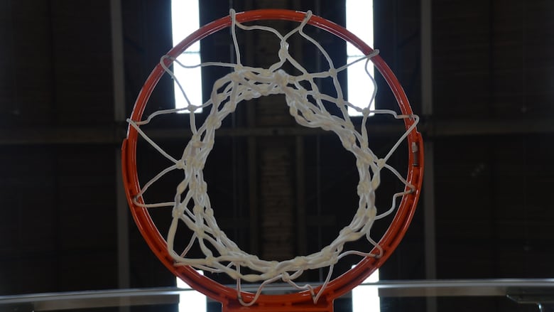 White mesh hangs from an orange basketball hoop.