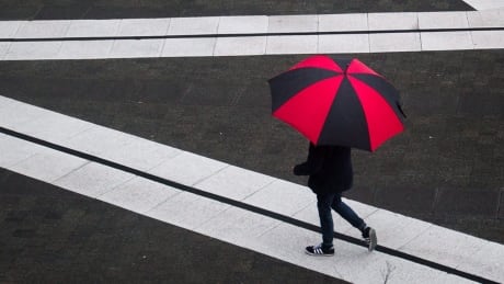 A pedestrian carrying an umbrella walks across the plaza at Central City as rain falls in Surrey, B.C.. on March 28, 2017. BC Daily Life 20170328