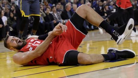 Raptors' centre Jonas Valanciunas reacts after injuring his hand during Toronto's win over the Golden State Warriors on Wednesday. He had surgery Thursday and is expected to be out at least four weeks. Raptors Warriors Basketball
