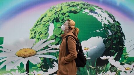 A woman wearing a protective pollution mask walks past a billboard in Beijing on March 20, 2017. The last large coal-fired power plant in Beijing has suspended operations, with the city's electricity now generated by natural gas, the state news agency reported as smog enveloped the Chinese capital this past weekend. / AFP PHOTO / NICOLAS ASFOURI (Photo credit should read NICOLAS ASFOURI/AFP/Getty Images) AFP_MT67V
